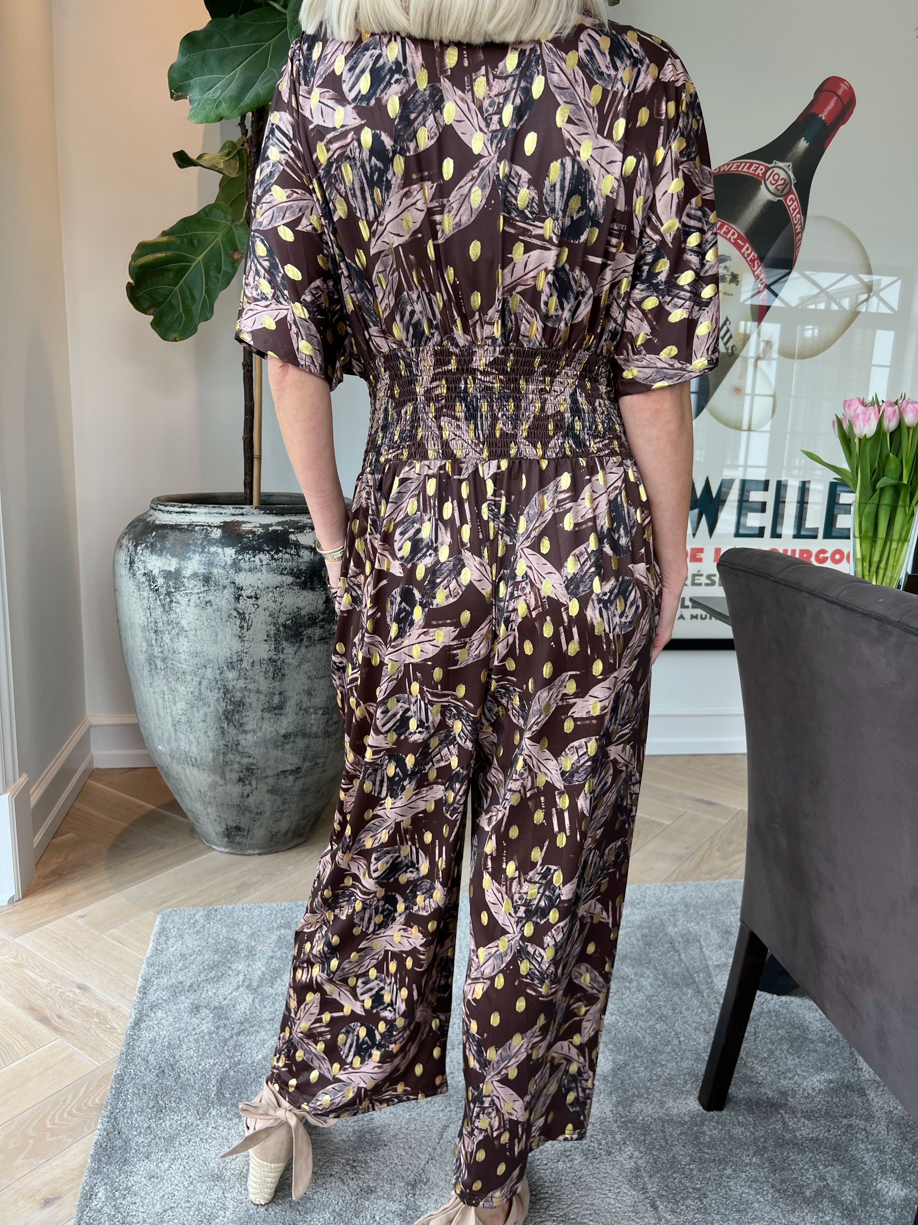 Pams Leafage Jumpsuit - Elastisk jumpsuit i lövmönster med guldfärgade tofsar